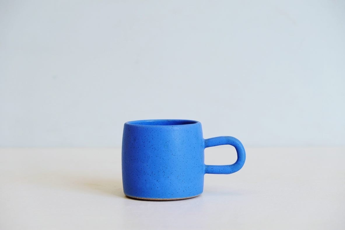 A little mug with a round handle dipped entirely in a in a sky blue glaze
