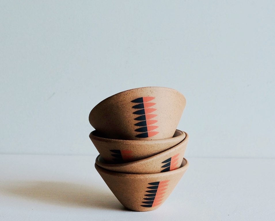 A stack of ceramic bowls with a black and red geometric and floral pattern