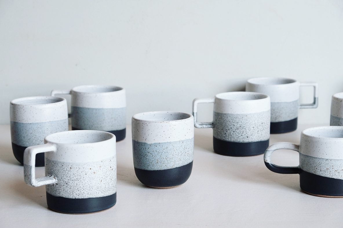 A handmade ceramic cup with a sparkling black, grey and white glaze dip.